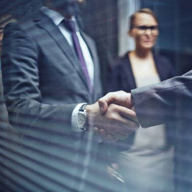 Close-up,Of,Businessmen,Handshaking,On,Background,Of,Woman